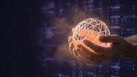 Hand holding glowing digital network sphere with connected lines against blurred city skyline, representing global connectivity, data technology, and business innovation.