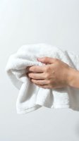 Hands holding soft white towel against clean background for spa wellness bathroom hygiene and personal care concepts.