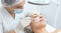 Professional cosmetologist performing facial injection treatment on female patient in modern medical clinic with sterile equipment and safety protocols.