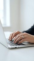 Close-up of hands typing on laptop keyboard in modern office workspace for business productivity and remote work applications.
