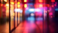 Blurred urban night scene with vibrant red and blue bokeh lights creating atmospheric mood. Empty corridor with glowing neon illumination reflects modern city nightlife.