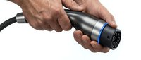 Male hands holding electric vehicle charging connector plug on white background isolated for eco-friendly transportation design projects.