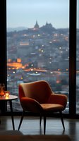 Cozy velvet armchair by panoramic window overlooking evening cityscape with blurred lights and historic architecture silhouette, candlelit ambiance for luxury interior.