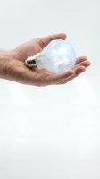 Hands holding glowing light bulb with bright filament against white background symbolizing innovation creativity and bright ideas for business concepts.