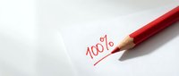Red pencil writing 100 percent on white paper for academic grading, business evaluation, and educational assessment concepts.