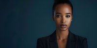 Professional African American businesswoman in black blazer against dark blue background for corporate marketing and leadership concepts.