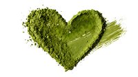 Green matcha tea powder arranged in heart shape on white background, symbolizing healthy lifestyle and natural wellness.