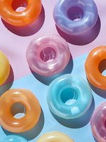 Colorful glazed donuts on pastel background with harsh shadows creating modern minimal composition. Sweet treats arranged in geometric pattern.