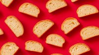 Sliced bread pieces arranged on vibrant red background, showcasing golden crust and soft interior texture for food photography or bakery marketing.