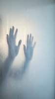 Silhouette of hands pressed against frosted glass surface creating mysterious shadow effect with soft lighting and textured background for creative projects.