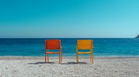 Two colorful chairs on pristine beach with turquoise ocean water and clear blue sky, summer vacation relaxation concept for travel and leisure designs.