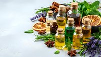Essential oils in glass bottles with fresh herbs, spices and dried citrus for aromatherapy, natural wellness and holistic healing treatments.