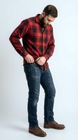 Caucasian male model wearing red plaid flannel shirt and dark denim jeans, buttoning shirt against white background for casual menswear fashion and lifestyle advertising.