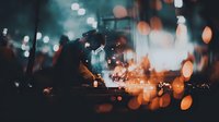 Welder at work with sparks flying in dark industrial setting, dramatic bokeh lights creating atmospheric mood for construction industry.