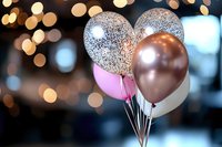 Festive metallic and pink balloons with silver glitter pattern against blurred bokeh lights background create elegant party atmosphere.