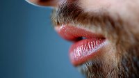 Close-up of masculine lips with stubble beard against blue background, showing texture and detail for beauty, cosmetic, or healthcare concepts.