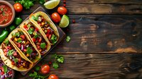 Mexican street tacos with meat, fresh vegetables and herbs on rustic wooden background with salsa sauce and lime wedges. Copy space for menu or recipe.