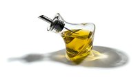 Elegant glass bottle with golden olive oil and metal pourer, isolated on white background with soft shadow, for culinary and food design.