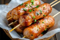 Grilled sausages on wooden skewers with fresh herbs in basket, ready to serve at barbecue party or outdoor cooking event.