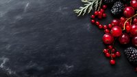 Fresh red currants and blackberries with green herbs on dark slate background with copy space for text, food photography styling for menu design.