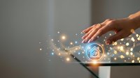 Hand touching digital tablet with glowing home automation icon and light particles for smart house technology and IoT control applications.