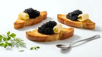 Toasted bread slices topped with creamy butter and luxurious black caviar, garnished with fresh herbs and served with a silver spoon for appetizers and gourmet dining.
