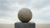 Large stone sphere balanced on concrete pedestal in minimalist desert landscape with overcast sky, suitable for architectural visualization and contemporary art projects.