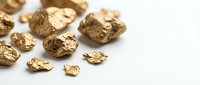 Golden nuggets scattered on white surface representing wealth, mining industry, precious metals investment and financial success concepts.