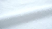 Close-up of white textured fabric with diagonal folds and soft shadows, suitable for backgrounds, textile design, and product photography.