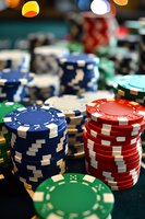 Stacks of colorful poker chips on green felt table with blue, red, and green tokens in casino setting, shallow depth of field creates dramatic gaming atmosphere.