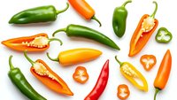 Fresh colorful chili peppers collection with sliced pieces showing seeds and flesh isolated on white background for culinary design projects.