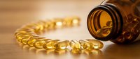 Golden omega-3 fish oil capsules spilling from amber glass bottle on wooden surface. Health supplement vitamins for wellness and nutrition support.