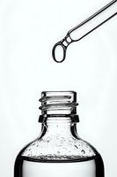 Glass dropper bottle with liquid medicine and pipette against white background, minimalist black and white pharmaceutical still life photography.