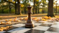 Wooden chess king piece standing on outdoor chessboard surrounded by autumn leaves in park setting with golden sunlight and trees in background.