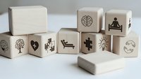 Wooden blocks with mental health and wellness symbols including brain, meditation, puzzle pieces for therapy and mindfulness concepts.
