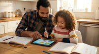 African American father helping young daughter with homework using digital tablet in modern kitchen during homeschooling session.