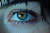 Close-up of striking blue and amber heterochromatic eye with dark lashes and fair complexion skin. Suitable for ophthalmology, genetics, beauty, and medical educational materials.