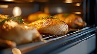 Golden roasted chicken with crispy skin cooking in modern oven with warm lighting. Professional kitchen equipment for culinary preparation and food photography.