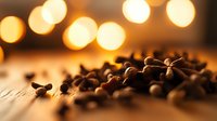 Roasted coffee beans scattered on wooden surface with warm bokeh lights in background creating cozy atmosphere. Suitable for cafe marketing and food blogs.