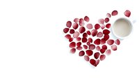 Red rose petals arranged in heart shape with white coffee cup on white background, romantic morning concept for Valentine's Day and anniversary celebrations.