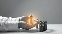 Young woman in golden light emerging from cupped hands of person in white shirt, surrounded by dark wooden figures representing community, teamwork, and human connection for business and leadership concepts.