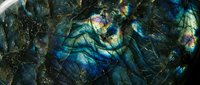 Stunning labradorite mineral surface displaying vibrant blue and green iridescent flashes with natural crystalline texture for luxury design projects.