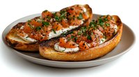 Fresh bruschetta topped with diced tomatoes, herbs and cheese on toasted bread slices served on white plate for appetizer or snack preparation.
