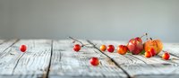 Fresh sweet cherries scattered on rustic wooden table with soft natural lighting, creating minimalist food composition with selective focus and bokeh effect.
