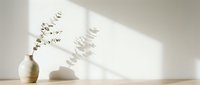 Minimalist still life with dried eucalyptus branches in ceramic vase, white sphere, and soft shadows on neutral background for home decor and interior design projects.