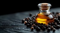 Aromatic essential oil in glass bottle surrounded by scattered black peppercorns on dark wooden surface, dramatic lighting highlights golden liquid.
