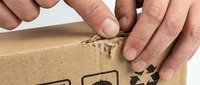 Male hands opening cardboard shipping box with recycling symbol, close-up of package delivery and unboxing process for logistics and e-commerce.