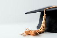 Black graduation mortarboard cap with gold tassel on white background, closeup view showing academic achievement and educational success milestone.