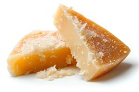 Chunks of aged parmesan cheese with crystalline texture and rich golden color showing natural breaks and crumbles on white background, macro food photography.