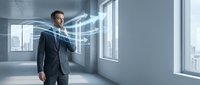 Young Caucasian businessman in dark suit manipulating holographic digital interface with glowing blue light trails in modern office interior.